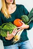 Woman holding fruits and vegetables in her arms