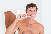 Man brushing her teeth with electric toothbrush