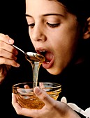 Young girl eating honey or syrup