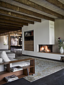 Fireplace and rustic wooden ceiling beams in elegant lounge
