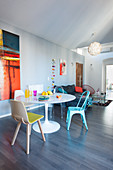 Round dining table and various chairs in front of sofa in open-plan interior