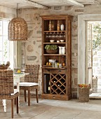 Crockery in cabinet with shelves and wine rack against stone wall in rustic dining area