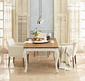 Country-house table and armchairs in front of French windows with vintage shutters