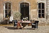 Round stone table and black outdoor armchairs outside vintage country house