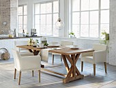 Rustic dining table and white upholstered chairs in open-plan kitchen with industrial glazing