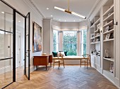 Fitted shelving, herringbone parquet and seating area in window bay in classic interior
