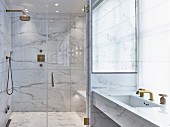 Glamorous modern bathroom with marble and gilt elements and glass doors