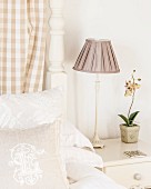 Nachttischlampe mit gerafftem Lampenschirm neben einer Orchidee