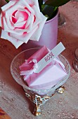 In rosafarbenem Papier verpackte Seife mit Etikett neben einer Rose