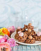 Easter arrangement of chocolate cornflake cakes on plate amongst ranunculus flowers