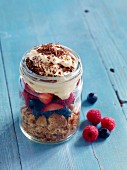Layered berry trifle with vanilla cream in a glass jar