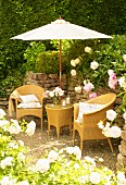 Romantic seating area with wicker furniture below parasol against stone wall