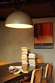 Large hemispherical lamp above stacked books on dining table
