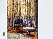 Classic Eames Lounge Chair with black leather upholstery and matching footstool in front of curtain