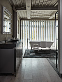 Metal washstand and free-standing bathtub in loft-apartment bathroom with vertical louvre blinds
