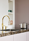 Gold sink tap fitting in minimalist kitchen