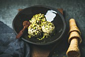 Homemade pistachio ice cream scoops with crashed pistachio nuts in dark plate