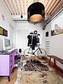 Schmaler Vorraum mit Garderobe, Fahrrad, lila Schreibtisch, Vintage Drehstuhl, Holzbank und Tierfellteppich