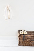 Cardigan hung on wall above white shoes on wicker trunk