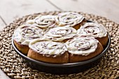 Cinnamon and cardomom buns in a pan with vanilla cream cheese frosting