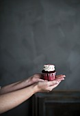 A red cupcake being held in a woman hands