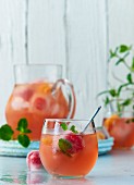 Fruchtige Sommerbowle mit Granatapfelsaft, Mineralwasser, Minze und Eiswürfeln mit eingefrorenen Beeren