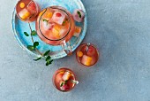Fruchtige Sommerbowle mit Granatapfelsaft, Mineralwasser, Minze und Eiswürfeln mit eingefrorenen Beeren