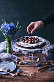 Woman putting chocolate eggs as decoration on top of Swedish chocolate cake on a cake stand