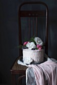 Geburtstagstorte mit Cremefrosting und Blütendeko auf Stuhl