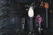 Variety assortment of raw uncooked colorful rice white, black, brown, pink in black spoons and scoop over wooden background