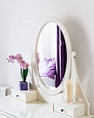 Ovaler Spiegel auf einem Schminktisch mit violetter Deko