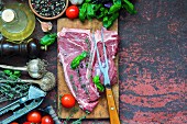 Raw T-bone steak with various ingredients