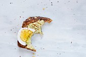 Missing bite of toasted bread with avocado and hard boiled egg