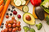 Avocado und rote Trauben, umgeben von Obst und Gemüse