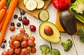 Avocado and red grapes surrounded by fruits and vegetables