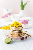 A pile of small pancakes and mango cubes