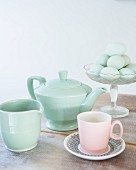 Retro teapot, milk jug and pink teacup in front of eggs in glass bowl
