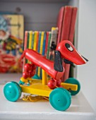 Red retro pull-along dachshund in front of colourful children's books