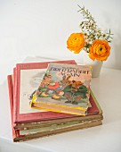 Retro children's books next to posy in beaker on white children's table