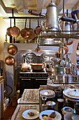 Antique cooker, copper pans and open-fronted shelves in kitchen