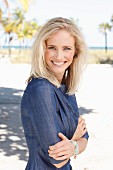 A blonde woman wearing a denim dress on the beach