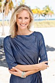 A blonde woman wearing a denim dress on the beach