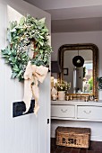 Wreath on open front door with view of gilt-framed mirror in hall