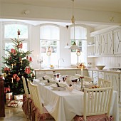 Festively set table and Christmas tree in country-house kitchen