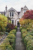 Garden path lined with box hedges leading to house