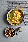 Vegan vegetable pilau in a pan and a bowl of mixed nuts and cranberries