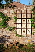 Kunstwerk an einer Steinmauer im mediterranen Garten