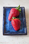 Two strawberries on a blue plate