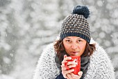 Frau hält Tasse mit heißem Getränk im Schneetreiben