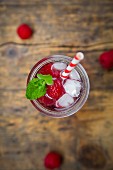 Raspberry champagne in glass, drinking straw, mint and raspberries
